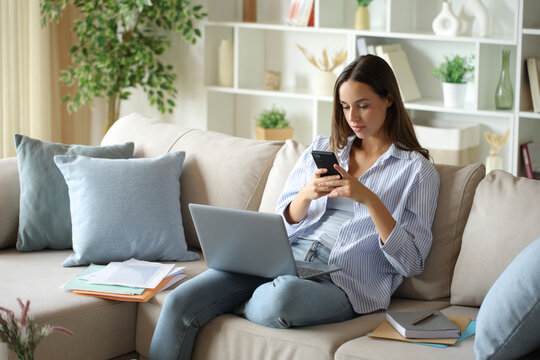 Telecommuter checking phone woriking at home