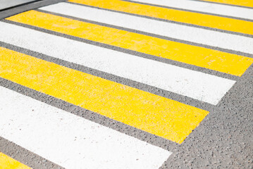 Fototapeta premium A close-up view of a crosswalk featuring alternating yellow and white stripes on a concrete surface.