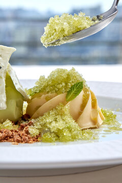 Gourmet ice cream dessert with refreshing lemon granita, meringue and crumble on white plate. High-end restaurant plating isolated on white background.