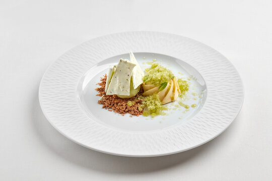 Gourmet ice cream dessert with refreshing lemon granita, meringue and crumble on white plate. High-end restaurant plating isolated on white background.