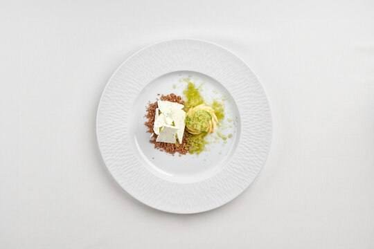 Gourmet ice cream dessert with refreshing lemon granita, meringue and crumble on white plate. High-end restaurant plating isolated on white background.