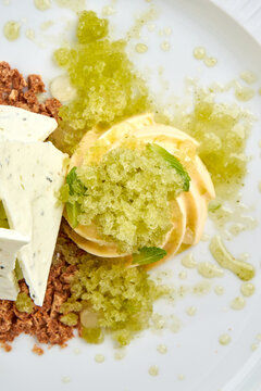 Gourmet ice cream dessert with refreshing lemon granita, meringue and crumble on white plate. High-end restaurant plating isolated on white background.