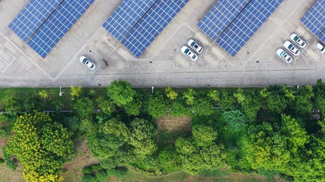Close overhead view of parked cars beside solar carports and trees
