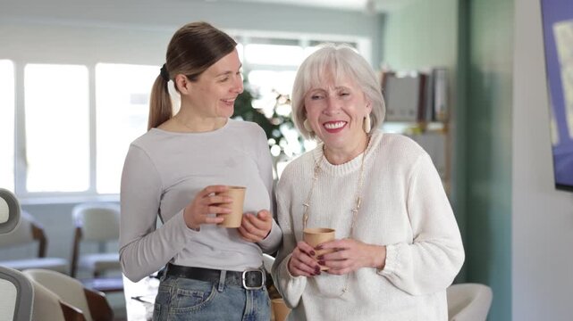 Two businesswomen drink coffee and discuss news during a break in the office. Coffee break . High quality 4k footage
