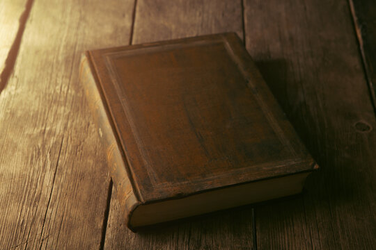Old book on wooden table, close-up.