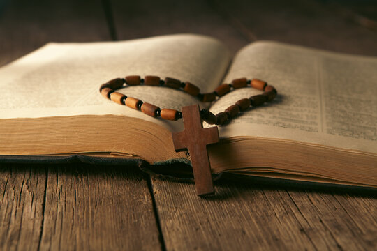 Bible and wooden rosary on wooden table, closeup