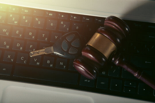 Gavel and car keys on the keyboard of a laptop computer.