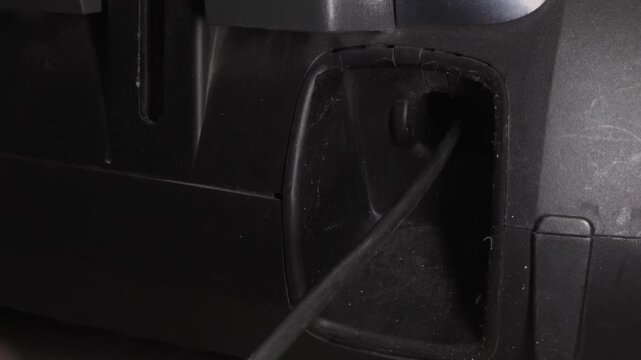 Male hand takes out and unwinds power cord electrical cable of bagged vacuum cleaner. Person extending power cord from compartment. Cleaning equipment.