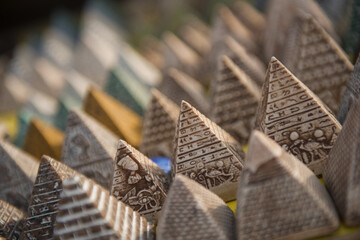 Close up of handcrafted miniature pyramid souvenirs covered in hieroglyphs and deity carvings displayed in rows at an Egyptian market stall ideal for © .shock