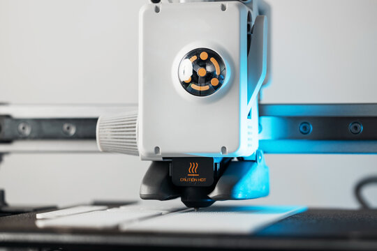 3D printer head printing a detailed white plastic component