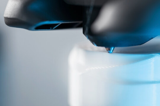 Extreme macro shot of 3D printer nozzle printing white plastic object