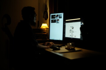 Silhouette of Designer Working at Computer in Dark Creative Studio © Mozecc