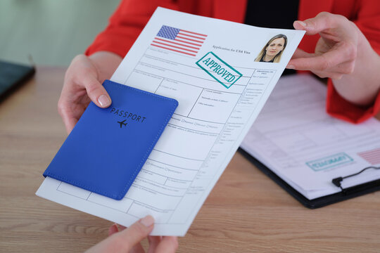 Woman agent gives passport and approved visa application to client in office. Female applicant receives legal documents to travel to USA in embassy