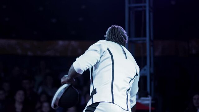 African-American man performs dynamic hat juggling act on stage for live audience, showcasing impressive acrobatic skill and entertainment in circus performance slow motion