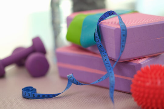 Workout area contains collection of home training accessories. Pair of dumbbells by flexible measuring tape sturdy yoga blocks and small massage ball