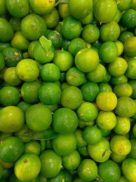 Fresh green limes piled together, highlighting natural citrus texture, vibrant color variation and organic produce for culinary use.