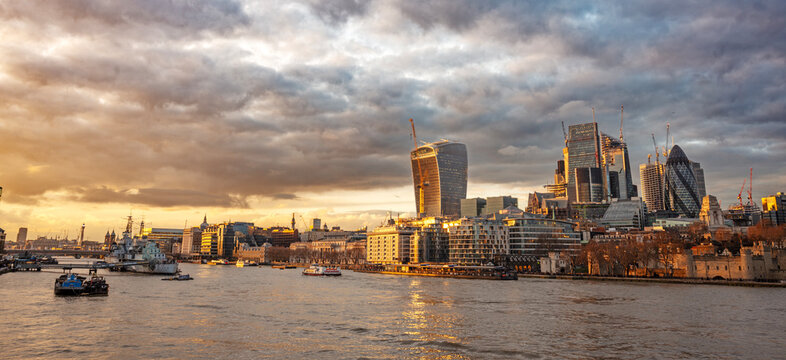 Tower of London beside the River Thames with HMS Belfast and City skyscrapers under construction, contrasting historic heritage with modern development.