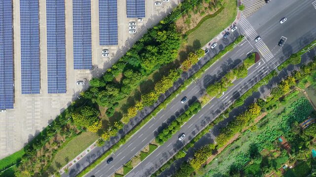 Top down aerial view of road traffic beside solar panel parking