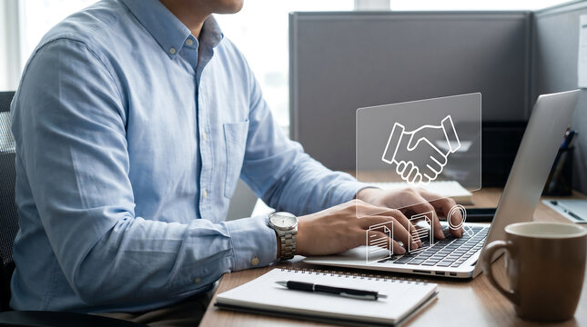 Professional man in a light blue shirt types on a laptop with digital handshake interface icons