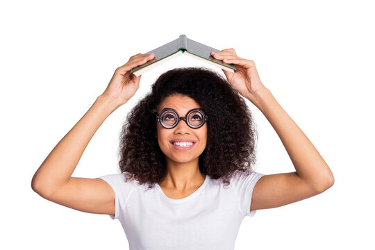 Close-up portrait of her she nice cheerful cheery smart clever intelligent wavy-haired girl nerd holding book over head reading materials isolated over light white pastel color background