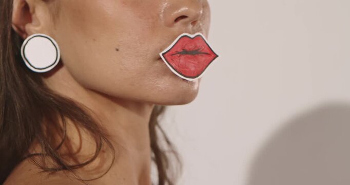 Close up of a woman wearing hand colored paper lips over her mouth with copy space. Concept creative fashion, beauty advertising, craft branding and editorial design.