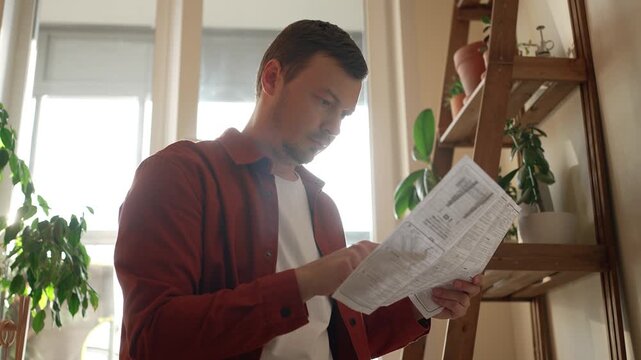 Young man carefully studying the instruction manual before starting to assemble a brand new tv wall mount bracket, meticulously preparing for home improvement and do it yourself tasks