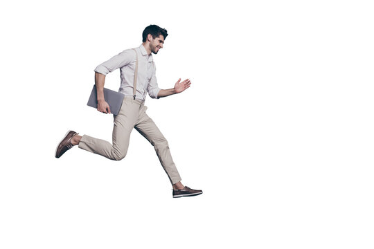 Full length profile side photo of cheerful excited guy hold computed know information about black friday discounts jump run fast wear modern clothing isolated over grey color background