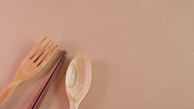 Top view of sustainable wooden cutlery including fork, spoon, and chopsticks with copy space on beige background