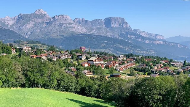 Hot Air Balloon Flying Over Alpine Village and French Alps Mountains