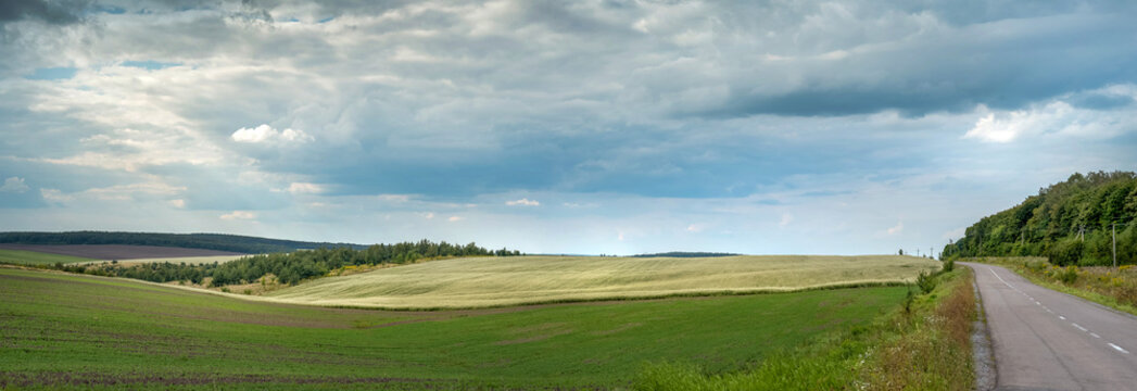 Scenic rolling hills and agricultural fields under cloudy sky