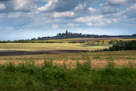 backdrop of hills of fields and other crops against the backdrop of a cloudy sky silhouette of the Monastery of Pidkamin, Lviv region