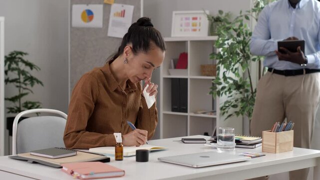 Sick businesswoman sneezing and working in the office