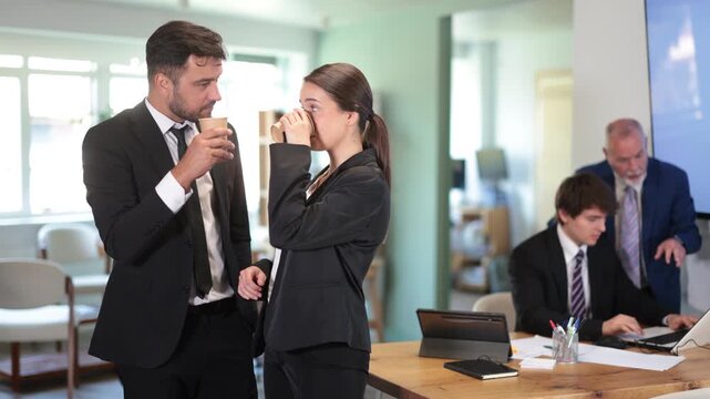 Adult man and woman colleagues drinking coffee in office during break from work 