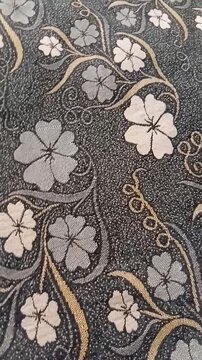 Close up of elegant floral jacquard fabric pattern with embroidered flowers and golden swirls