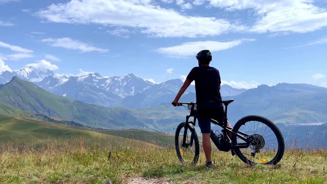 Mountain Biker Looking at Snow Covered Alps Peaks in Summer