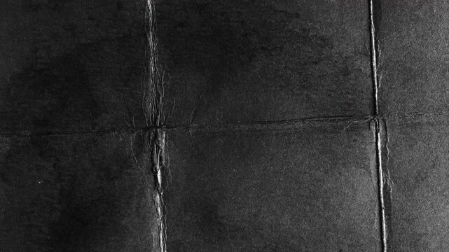 Abstract dark black paper texture with fold lines.