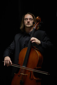 Vertical shot of focused Caucasian young adult man playing cello with eyes closed. Ideal for classical music concert promotion, acoustic performance marketing or arts education