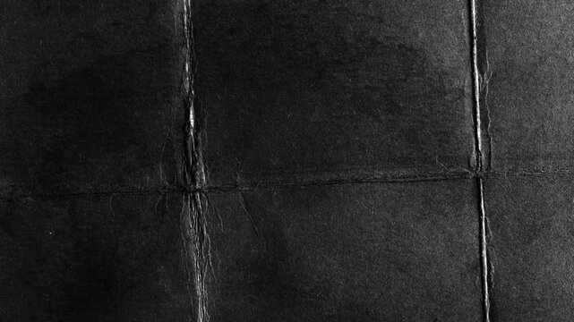 Abstract dark black paper texture with creases and folds.