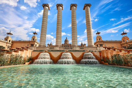 Barcelona, Spain. High pillar columns of the Magic fountain of Montjuic Mountain by the museum of Catalonia. Fountain pool summer day with cloudy sky.