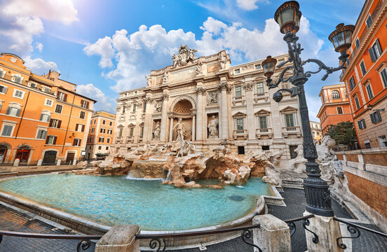 Ancient Trevi Fountain in Rome, Italy. Majestic fountain with Roman statues at piazza in old medieval city among traditional italian houses and street lamps. Famous landmark. Touristic destination.