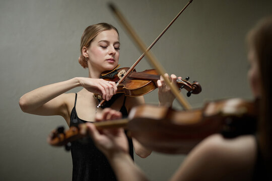 Young adult Caucasian woman playing violin during classical music performance rehearsal. Classical musician practicing string instrument for concert event promotion