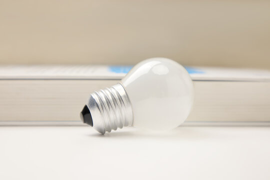 White light bulb on book representing idea, learning and innovation
