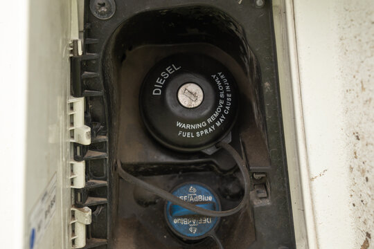 Vehicle's fuel compartment revealing the diesel fuel cap with a warning for spray and the adblue def (diesel exhaust fluid) cap