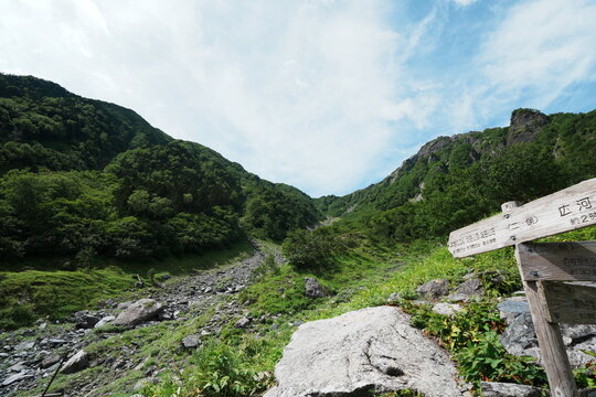 夏の南アルプスで岩がれの谷に開ける登山道と青空に伸びる筋状の雲