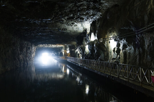 Walkway beside water channel inside historic stone tunnel in Kinmen