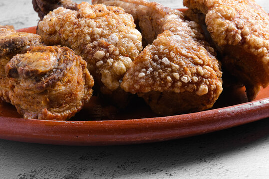 Chicharrones on a Clay Plate Over Gray Cement Surface with Copy Space
