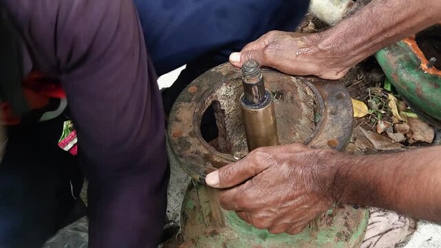 Technicians Sorting Metallic Fasteners from a clear plastic bag to repair a disassembled cast-iron centrifugal water pump, highlights the hands-on engineering workflow of outdoor machinery maintenance
