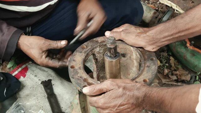 Two Technicians Fitting a Hex Nut onto a rusted flange bolt of a disassembled centrifugal water pump, showcasing precision mechanical engineering and manual industrial maintenance workflows.