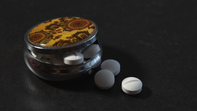 Pastillas para el dolor de cabeza dentro de un viejo pastillero
