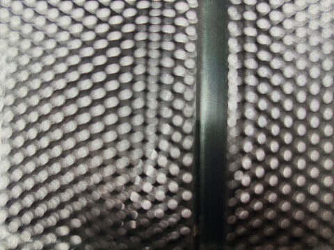 Closeup of a metallic speaker grille with a dark vertical frame